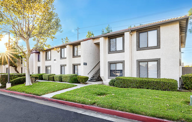 a row of apartment buildings with green grass and a sidewalk