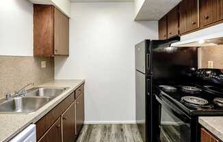 A kitchen with a black refrigerator and stove top oven.