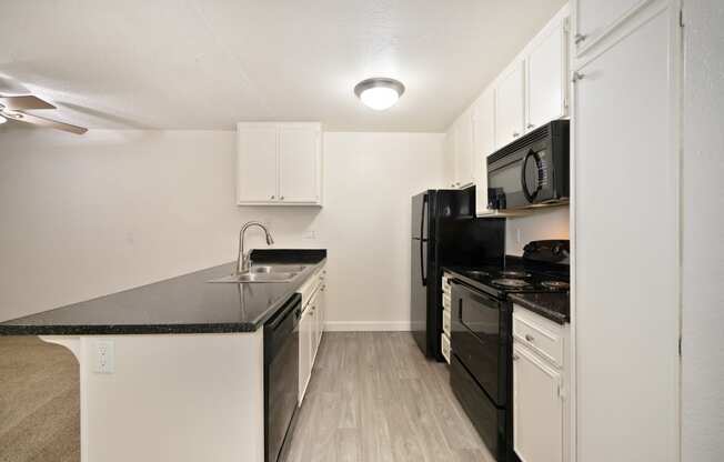 an apartment kitchen with black appliances and white cabinets