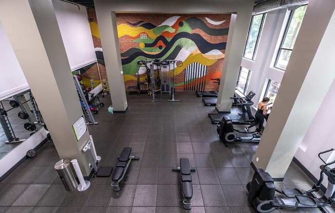 A gym with a variety of equipment including treadmills, weights and exercise machines.