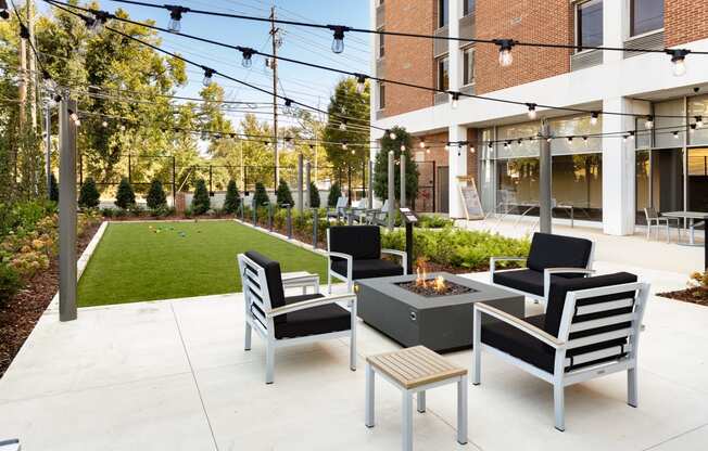 a patio with chairs and a fire pit in front of a building