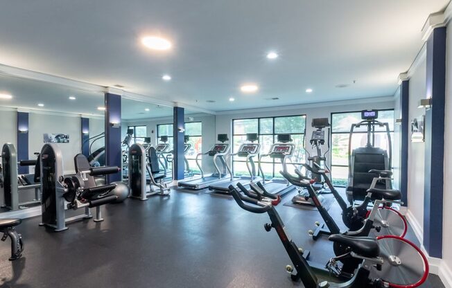 a gym with cardio equipment and weights in a building with windows