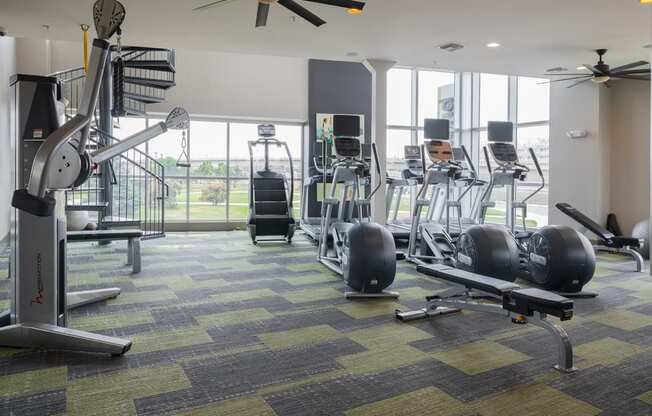 a gym with treadmills and other exercise equipment with a large window in the background