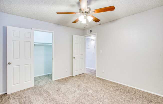 A room with a ceiling fan and carpeted floor.