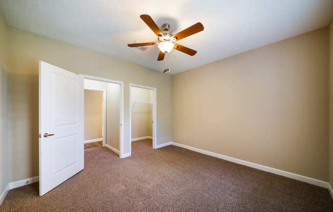 an empty room with a ceiling fan and a door to a closet