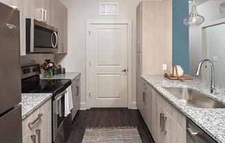 a kitchen with stainless steel appliances and marble counter tops at Promenade at Newnan Crossing, Newnan