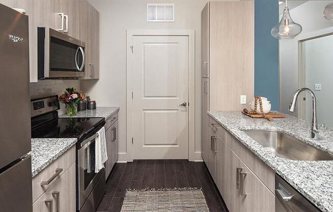 a kitchen with stainless steel appliances and marble counter tops at Promenade at Newnan Crossing, Newnan