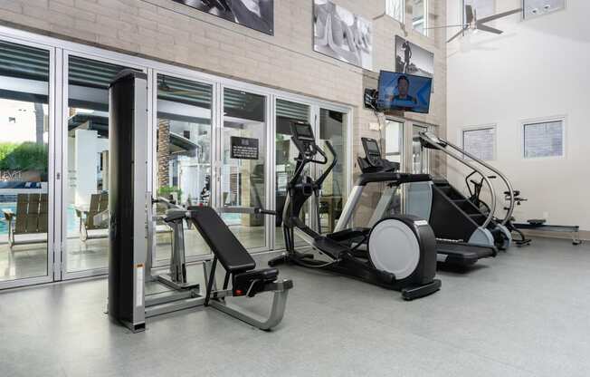 a gym with treadmills and other exercise equipment in a building with glass doors