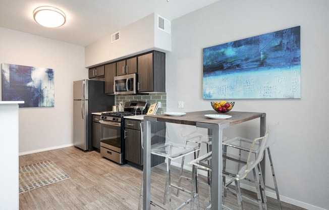 a kitchen with a bar with stools and a stainless steel refrigerator