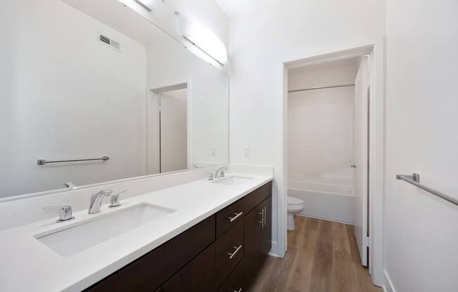 A white bathroom with a sink, mirror, and toilet.