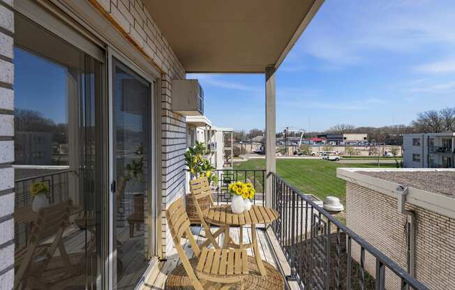 a balcony with a table and chairs and a view of a grassy area