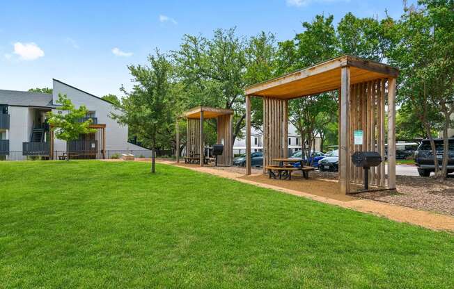 a group of wooden structures on a lawn with grass and trees