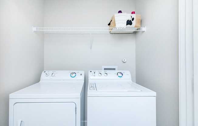 Two white front loading washing machines in a laundry room.