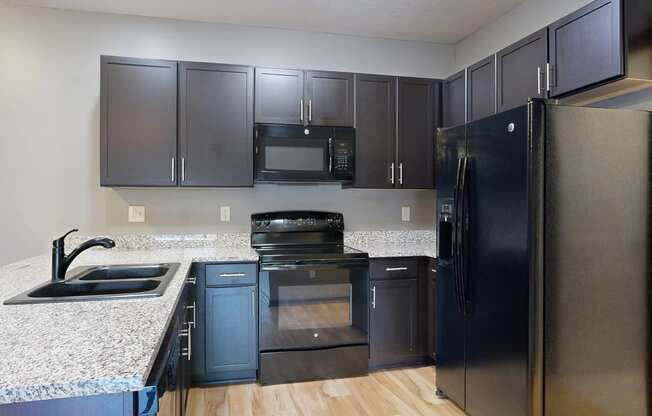 a kitchen with dark cabinets and granite countertops