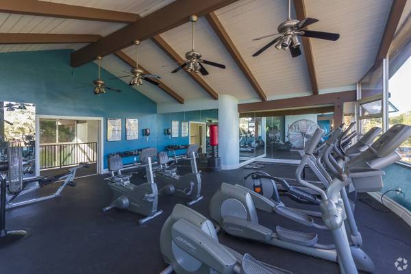 a room filled with lots of cardio equipment and ceiling fans