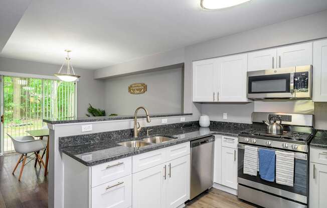 A modern kitchen with white cabinets and a granite countertop.