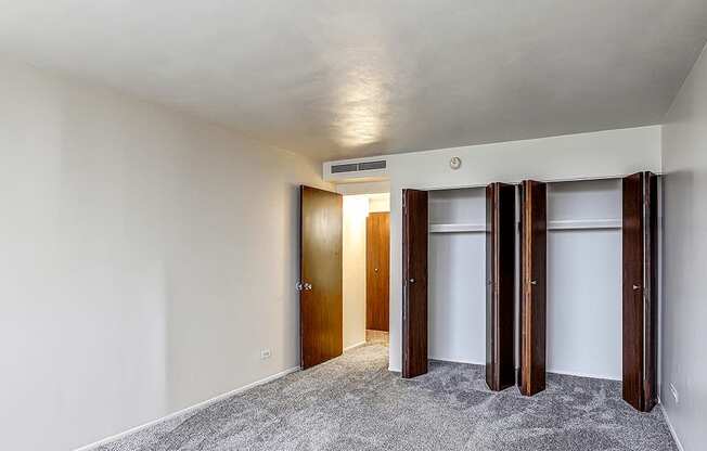 A room with a carpeted floor and a white ceiling with three doors.