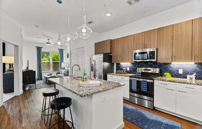 A modern kitchen with a granite countertop and stainless steel appliances.