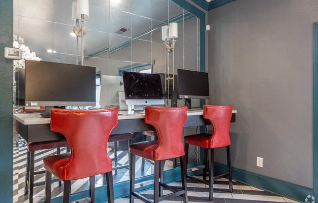 a computer desk with red chairs in front of a mirror