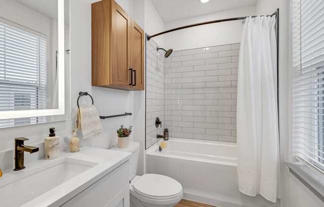 a white bathroom with white subway tile and a shower and a sink and a toilet at Meridian at CityPlace, Woodbury, MN 55125