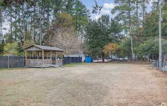 A small wooden pavilion sits in the middle of a grassy field.