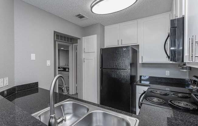 A kitchen with a black fridge and stove top oven.