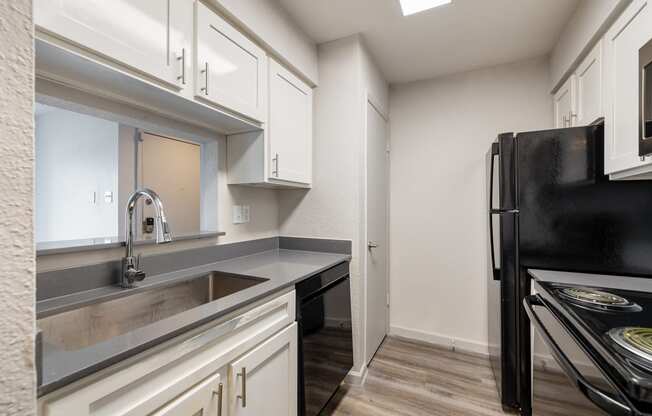 a kitchen with white cabinets and a sink and a refrigerator