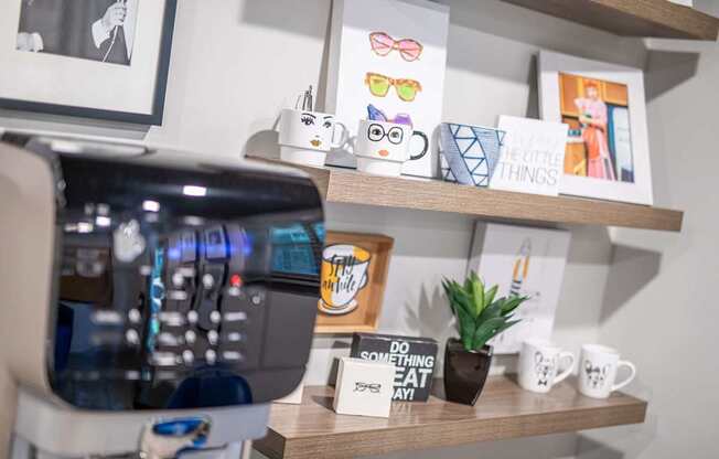 A coffee machine is on the left with a shelf above it holding a sign that says "Do something nice today" and a small potted plant.
