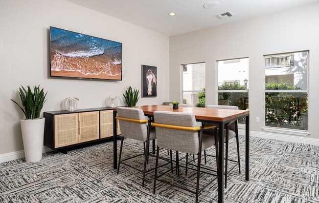 A room with a table, chairs, and a painting of a beach scene.