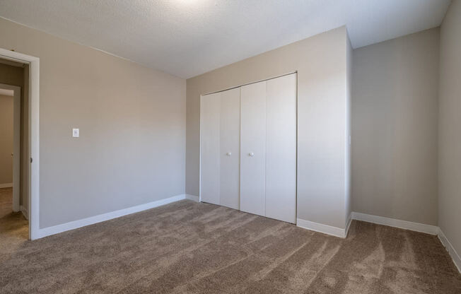 an empty room with white walls and mirrored closets