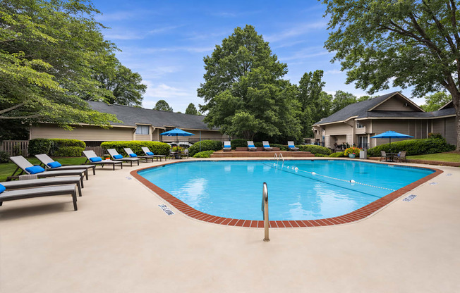 A swimming pool surrounded by lounge chairs and trees.