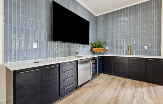 a kitchen with blue tiles and a large screen tv on the wall