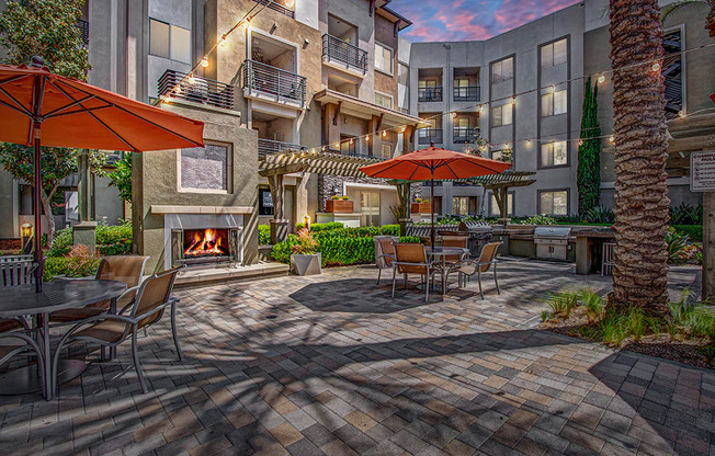 a patio with a fire place and tables with umbrellas