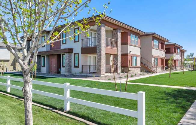 A white picket fence in front of a row of apartment buildings.