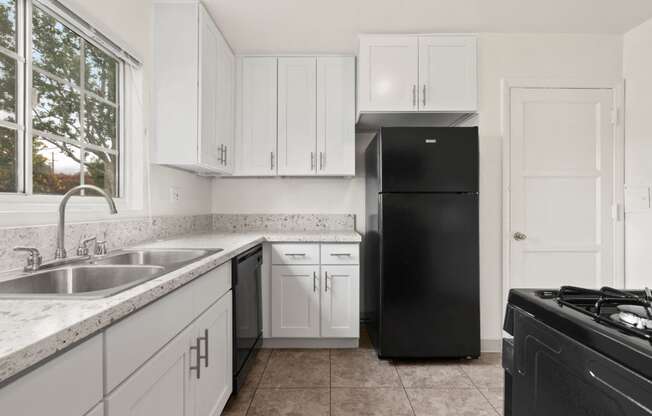 Van Nuys Apartments for Rent - Colonial Manor Modern Kitchen with Black Appliances, White Cabinetry, and Large Window