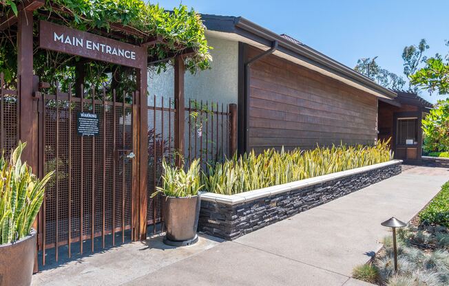 the entrance to the main entrance of a building with a fence and plants