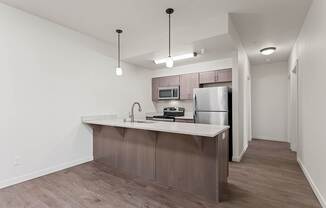 A kitchen with a refrigerator, microwave, and sink.