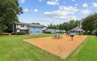 A park with a playground and picnic tables.