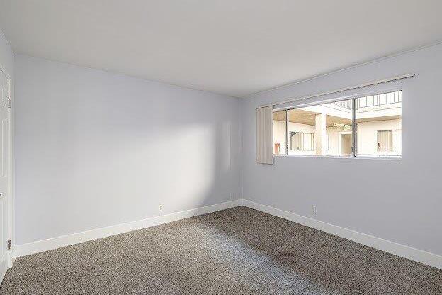 A room with a carpeted floor and a window letting in sunlight.