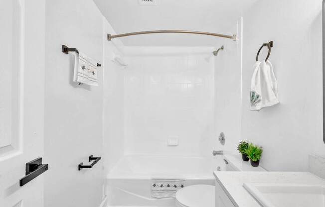 A white bathroom with a towel hanging on the towel rack.