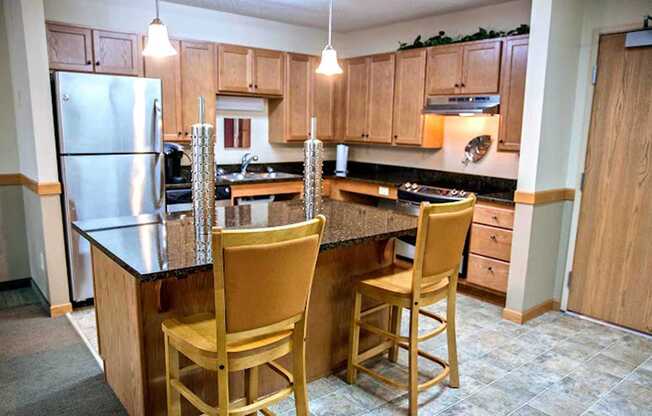 A kitchen with a refrigerator, two chairs, and a countertop.
