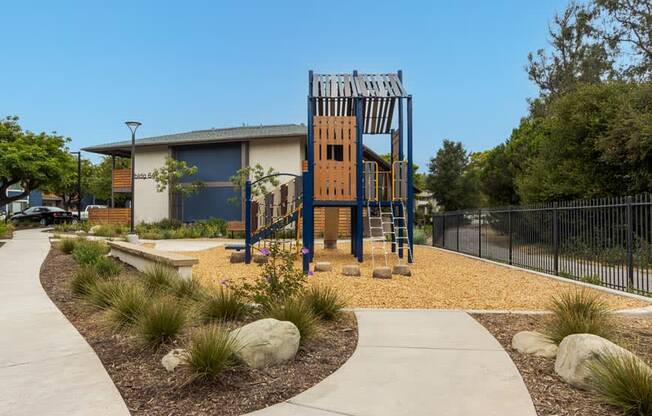 a playground with a wooden tower in front of a house