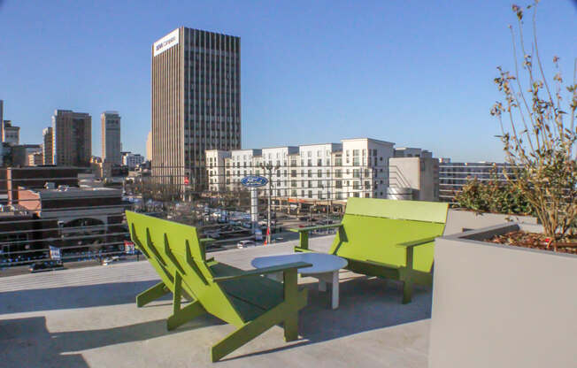 a patio with two green chairs and a table on a roof at 20 Midtown, Birmingham, AL, 35233