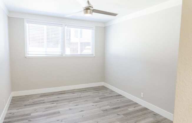 an empty room with wood floors and a window