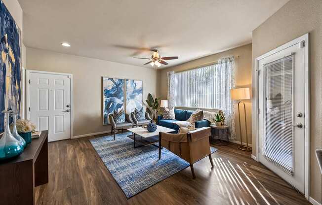 A living room with a blue rug and a wooden floor.