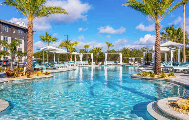 A large swimming pool surrounded by palm trees and lounge chairs.