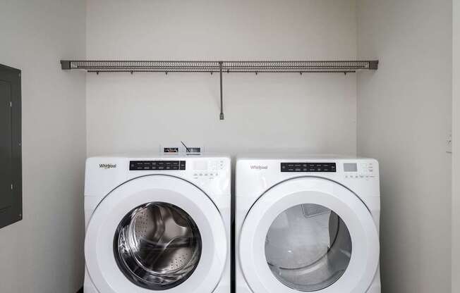 Two white Whirlpool washing machines in a laundry room.