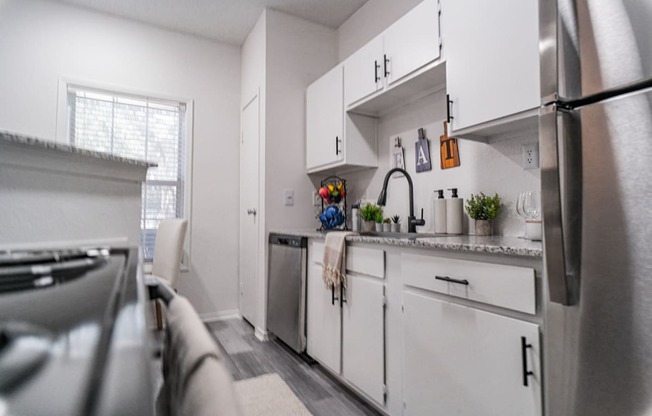 a kitchen with white cabinets and stainless steel appliances and a window