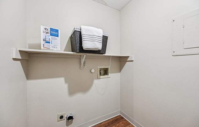 A white shelf with a basket and towels on it.