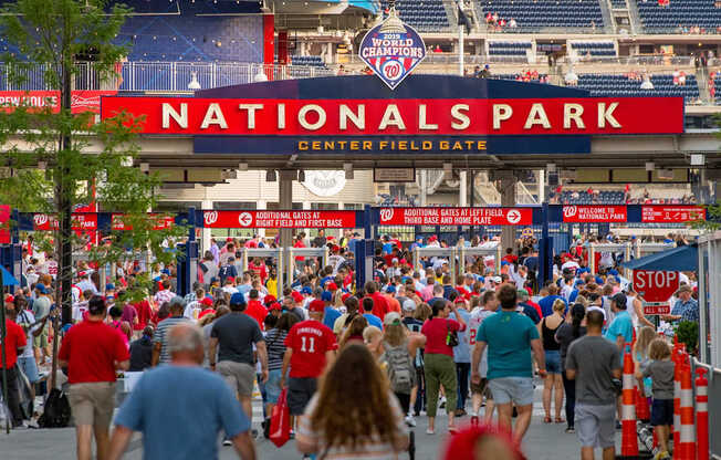 A large crowd of people are walking towards the entrance of Nationals Park.
